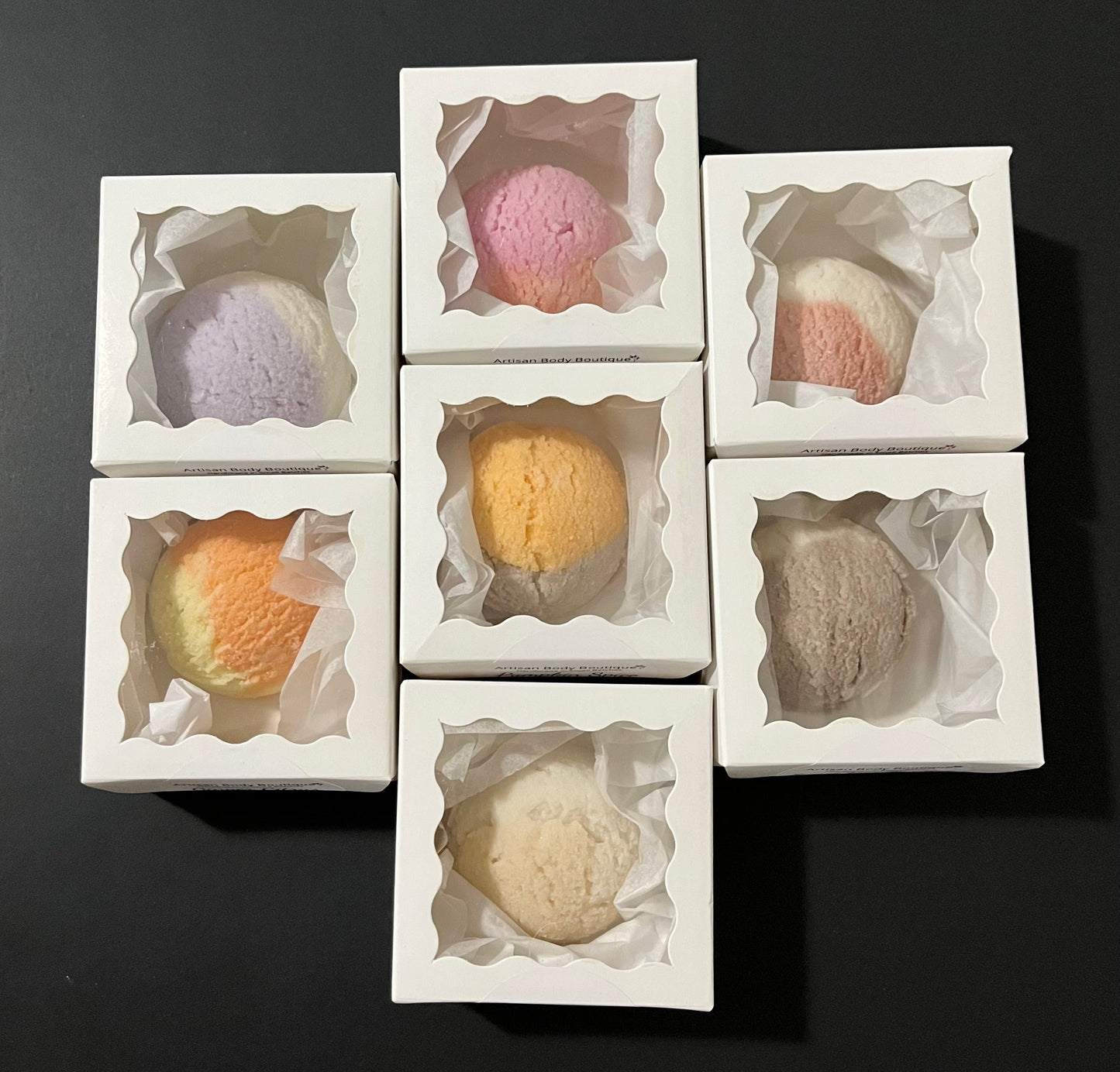 Top view of a cluster of bath truffles arranged in white window boxes, showcasing their luxurious, round shape and delicate texture.