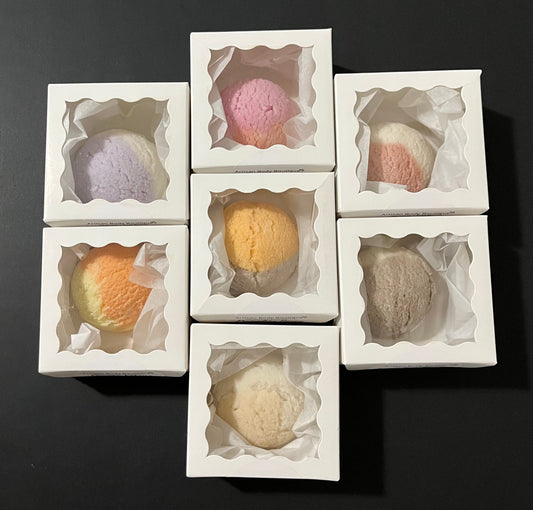 Top view of a cluster of bath truffles arranged in white window boxes, showcasing their luxurious, round shape and delicate texture.